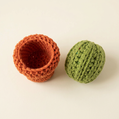 Removable crochet cactus top beside the hollow terracotta-orange storage pot